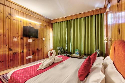 a bedroom with a bed with a towel animal on it at MHA hotel ever green manali in Manāli