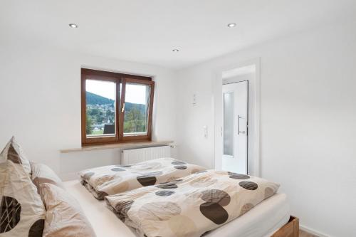 a white bedroom with a bed and a window at Fewo Weitblick - Haus Sommerberg in Baiersbronn