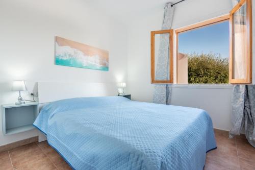a bedroom with a blue bed and a window at Appartamento Cerri in Badesi