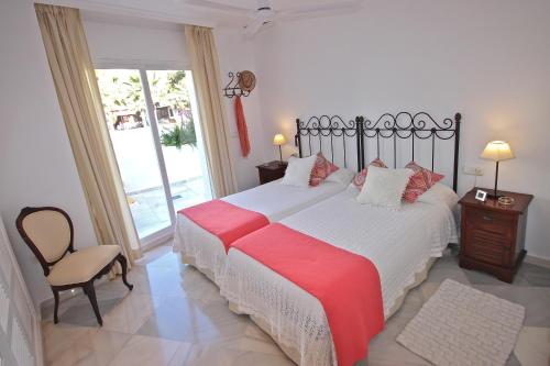 a bedroom with a bed and a chair and a window at Deluxe Apartment on the Beach in Marbella