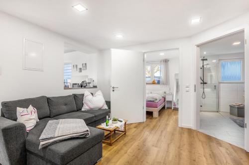 a living room with a gray couch and a room with a bedroom at Ferienwohnung Seyfried in Hardheim