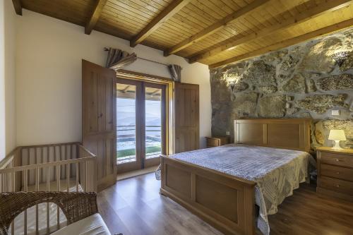 a bedroom with a bed and a stone wall at Casa De Basto in Gémeos