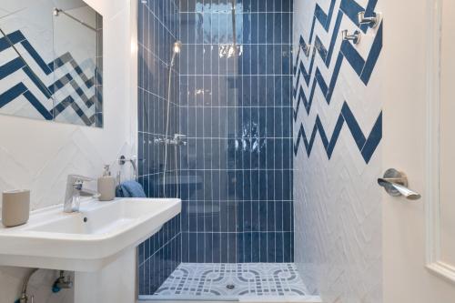 a bathroom with a sink and a shower with blue tiles at Casa Buganvilla in Barbate