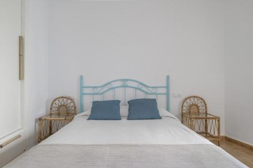 a white bed with two blue pillows on it at Casa Buganvilla in Barbate