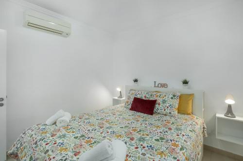 a white bedroom with a bed with a colorful bedspread at Vv Brisamar in Telde