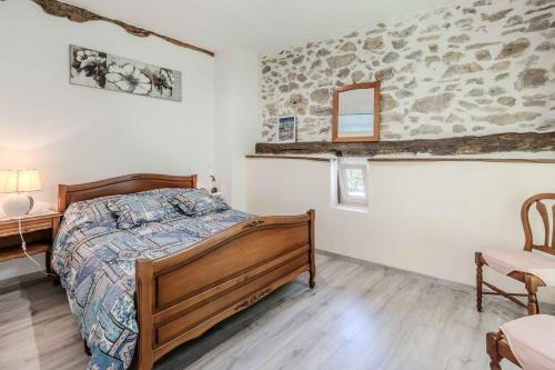 a bedroom with a wooden bed and a stone wall at Gite du Moulin - Ariège in Carla-de-Roquefort