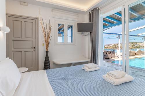 a white bedroom with a bed and a pool at Blue Waves View Andros in Andros