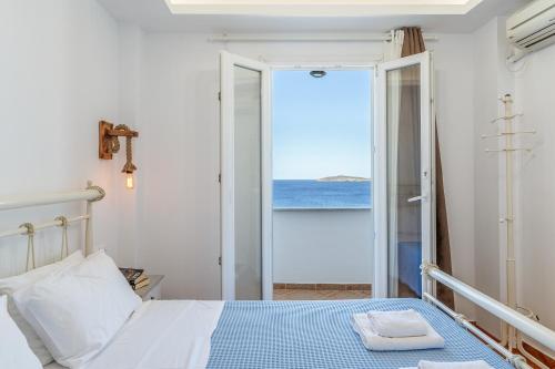 a bedroom with a bed and a view of the ocean at Blue Waves View Andros in Andros