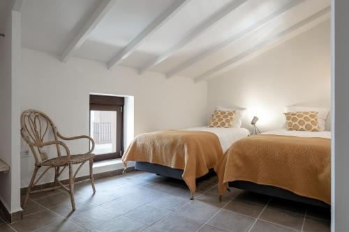 two beds in a room with a chair and a window at Casa Roques 16 in Jávea