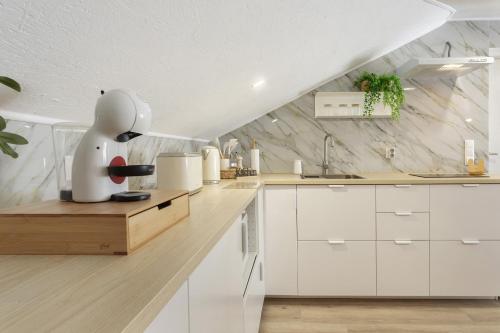 a kitchen with white cabinets and a marble wall at Sky and Sea Haven in Santa Cruz