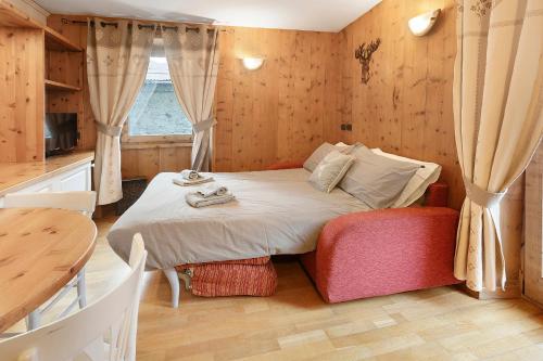a bedroom with a bed and a table and a window at Appartamento Le Cigamole in Valfurva