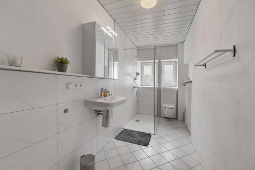 a white bathroom with a sink and a shower at Ferienwohnung Merzig in Merzig