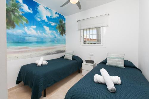 a bedroom with two beds and a painting of the beach at Luxury Sea view Apartment in Nerja