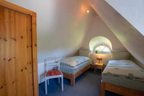a attic room with two beds and a window at Ferienwohnungen Appelhus in Pellworm