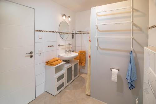 a white bathroom with a sink and a mirror at Haus Ruther - Wohnung 2 in Bad Saulgau