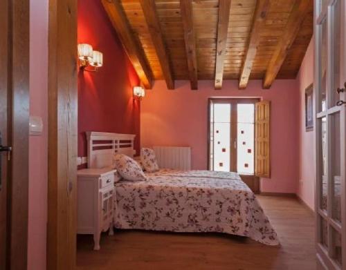 a bedroom with pink walls and a bed and a window at Montes De Alhama in Villarraso