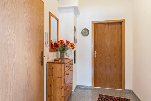 a hallway with a door and a vase of flowers on a dresser at Haus am Mühlenbach in Hilzingen