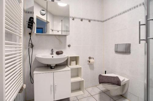 a white bathroom with a sink and a toilet at Bäckerhus - Ferienwohnung 5 in Wiek auf Rügen
