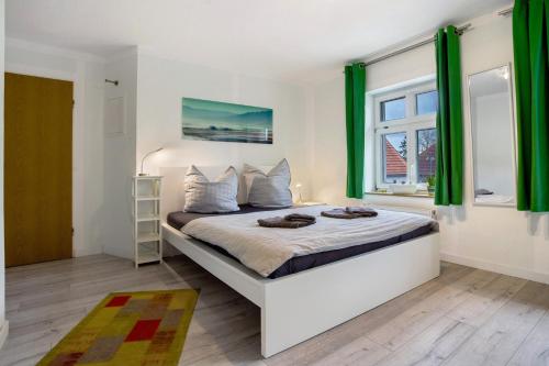 a bedroom with a large bed with green curtains at Bäckerhus - Ferienwohnung 5 in Wiek auf Rügen