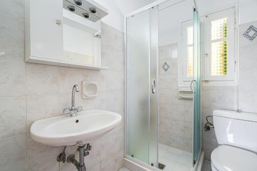 a white bathroom with a sink and a shower at Veroni's studio 1 in Vathi