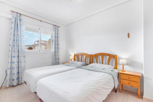 two beds in a white bedroom with a window at Viñamar 7 in La Mata