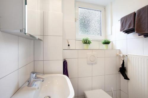 a bathroom with a sink and a toilet and a window at Ferienwohnung Keil in Balve