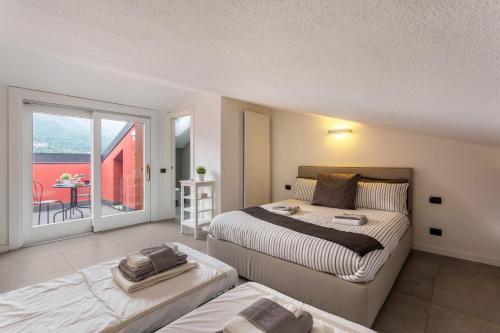 a bedroom with two beds and a balcony at New Eleven Apartment on Como Lake in Oliveto Lario