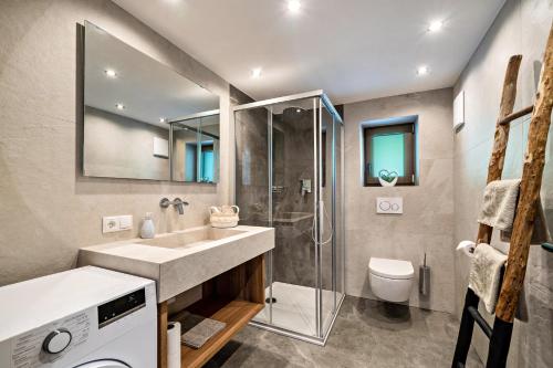 a bathroom with a sink and a shower and a toilet at Sunnseitn Lodge Apartment Alps in Moso