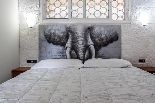 a bedroom with a bed with a painting of an elephant at Ca La Nyca in Tossa de Mar