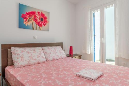 a bedroom with a bed with a pink blanket and a window at Ammos Tinos in Istérnia