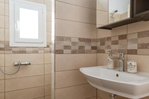 a bathroom with a sink and a window at Ammos Tinos in Istérnia