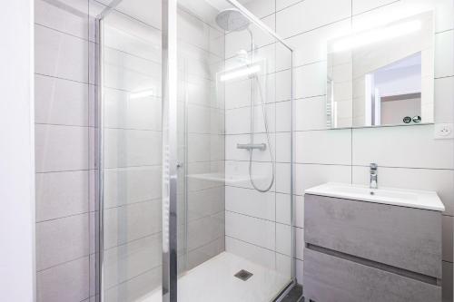 a white bathroom with a shower and a sink at Maison vélo et ski in Saint-Jean-de-Maurienne