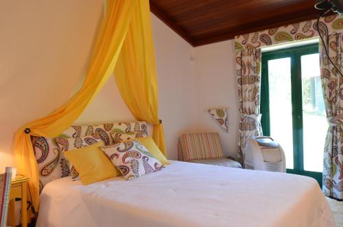 a bedroom with a bed with yellow curtains and a window at Quinta Pé Franco in Medrões
