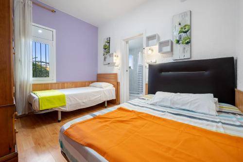 a bedroom with two beds and a large orange bed at Caseta de l'avi in Camarles