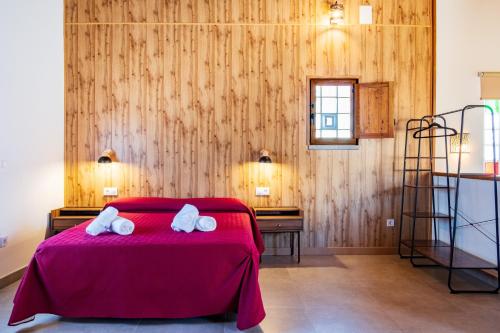 a bedroom with a red bed with two towels on it at Quercus in Navaluenga