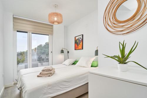 a white bedroom with a large bed and a window at Apartamento Playa Cabria in Almuñécar