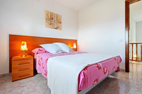 a bedroom with a pink and white bed and a nightstand at Casa Anglada in Calafell