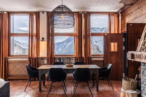 a dining room with a table and chairs and windows at Chalet D'albiez in Albiez-Montrond