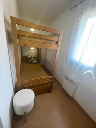 a small room with a bunk bed with a white stool at Les evettes 4-6 couchages in Flumet