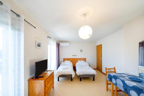 a bedroom with two beds and a flat screen tv at Les Mimosas - Appartement 05 in Cazaubon