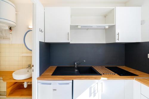 a kitchen with white cabinets and a sink at Les Mimosas - Appartement 05 in Cazaubon