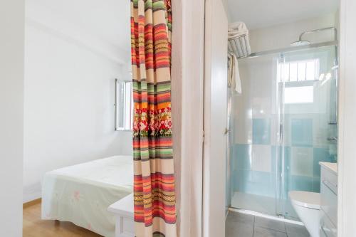 a bathroom with a shower curtain next to a bed at Retirosol Bungalow in Denia