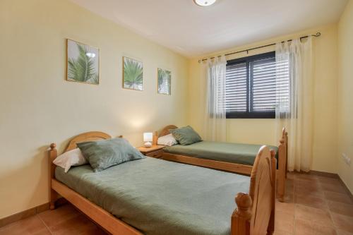 a bedroom with two beds and a window at Palm Serenity in Playa Paraiso