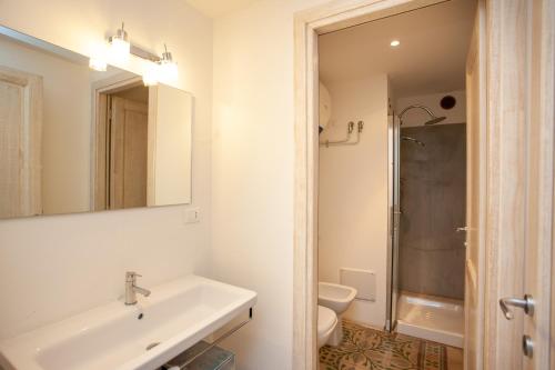 a bathroom with a sink and a toilet and a mirror at Hora Est in Orosei