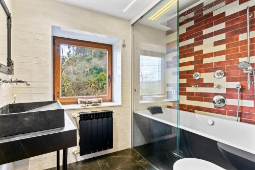 a bathroom with a sink and a tub and a window at El Bosque in Candamin
