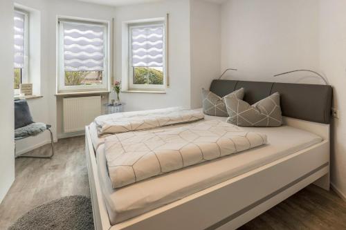 a large bed in a room with two windows at Ferienwohnung Griesbaum in Tengen