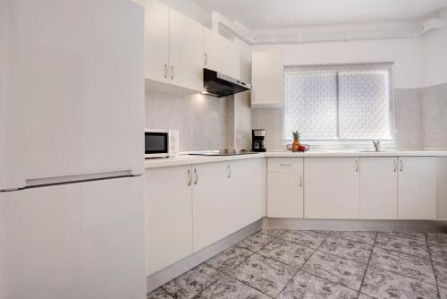 a white kitchen with white cabinets and a window at Casa Relax in Gran Tarajal