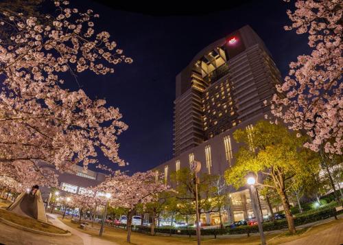 a bride and groom standing in a park withakura trees at Imperial Hotel Osaka in Osaka