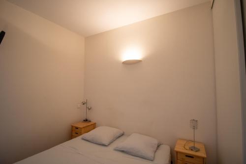 a bedroom with two beds and a light on the wall at Résidence Aria Marina Plage in Ajaccio