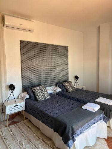 a bedroom with two beds and a large headboard at Villa Gení in La Victoria